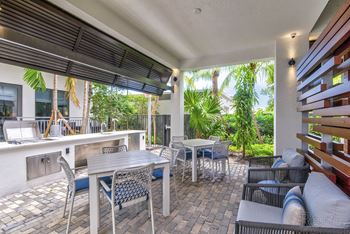 A patio with a table and chairs is covered by a roof at Mayla Pompano, Pompano Beach